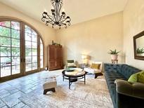 Bright living room boasts a decorative chandelier, neutral color palette, and access to the outdoor living space at 18805 E Loredo Ln, Rio Verde, AZ 85263