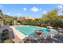 Backyard pool featuring decorative stone fire bowls, a stone surround, and mature desert landscaping at 20369 N 272Nd Ave, Buckeye, AZ 85396