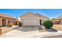 Tan house with a two-car garage and well-manicured landscaping at 15365 W Caribbean Ln, Surprise, AZ 85379