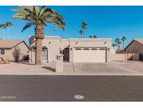Tan stucco house with a two-car garage and desert landscaping at 9714 E Indiana Ave, Sun Lakes, AZ 85248