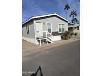 Mobile home exterior features gray siding, white trim, and a small front porch at 625 W Mckellips Rd # 115, Mesa, AZ 85201