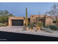 Desert landscape accents this stucco home with a dark garage door and stone accents at 10585 E Crescent Moon Dr # 19, Scottsdale, AZ 85262