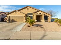 Single-story house with tan exterior, two-car garage, and desert landscaping at 8642 W Harmony Ln, Peoria, AZ 85382