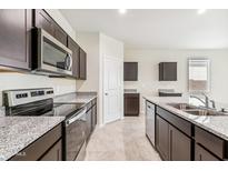 Modern kitchen with dark cabinetry, granite countertops, and stainless steel appliances at 1791 W Sombra Ave, Apache Junction, AZ 85120
