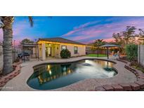 Inviting backyard oasis featuring a kidney-shaped pool, pergola, and lush landscaping at 21752 E Estrella Rd, Queen Creek, AZ 85142