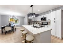 Modern kitchen with white cabinets, island, and dining area at 1743 W Butler Dr, Phoenix, AZ 85021