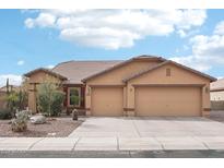 Beige house with two-car garage, landscaping, and a paved driveway at 3376 S 256Th Dr, Buckeye, AZ 85326