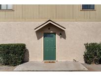 A close-up of the front door features a covered porch, green door, and manicured bushes at 8328 W Fairmount Ave, Phoenix, AZ 85037