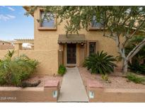 Inviting exterior of a tan two-story condo with a walkway, landscaping, and a brown door at 10426 N 11Th St # 3, Phoenix, AZ 85020