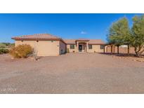 Single-story home with Spanish-style architecture, gravel driveway, and mature trees at 44429 N 1St Dr, New River, AZ 85087