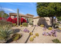 Landscaped front yard with desert plants and cacti surrounding a tan single-story home at 7654 E Quill Ln, Scottsdale, AZ 85255