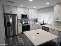 A modern kitchen featuring white cabinets, stainless steel appliances, and a kitchen island with a light countertop at 903 W Loughlin Dr, Chandler, AZ 85225