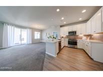 Modern kitchen featuring white cabinets, stainless steel appliances, a breakfast bar, and stylish tile backsplash at 14200 W Village Pkwy # 113, Litchfield Park, AZ 85340