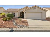 Tan house with a two-car garage and desert landscaping at 15077 W Vale Dr, Goodyear, AZ 85395
