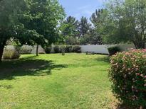 Lush backyard featuring mature trees, vibrant bushes, picnic table and white picket fence at 2207 W Hayward Ave, Phoenix, AZ 85021