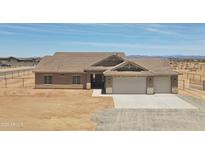Single-story home with desert landscaping, neutral toned exterior, and a three-car garage in a fenced lot at 22270 W Skinner Rd, Wittmann, AZ 85361