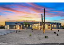 Stunning desert home featuring stone accents, a paver driveway, and a large saguaro cactus at sunset at 8110 E Saddle Horn Rd, Scottsdale, AZ 85255