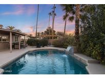 Inviting backyard oasis featuring a sparkling pool, waterfall, and pergola at 5201 E Winchcomb Dr, Scottsdale, AZ 85254