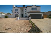 Two-story house with a gray-trimmed white exterior, a two-car garage, and a landscaped front yard at 6073 W Caribe Ln, Glendale, AZ 85306