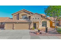 Charming two-story home featuring a three-car garage, stone accents, and landscaped front yard at 15727 W Rimrock St, Surprise, AZ 85374