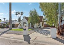 Charming home featuring a well-manicured lawn, palm trees, and a private driveway at 2209 E Weldon Ave, Phoenix, AZ 85016