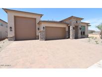 Beautiful single-story home featuring a 3-car garage, stone accents, and a paver driveway at 6818 N 190Th Ave, Waddell, AZ 85355