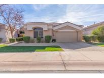 Single-story home with tan exterior, landscaped yard, and a two-car garage at 8687 E Tuckey Ln, Scottsdale, AZ 85250