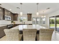Kitchen island with quartz countertops, wicker barstools, pendant lights, and backyard view at 9230 N 104Th Pl, Scottsdale, AZ 85258
