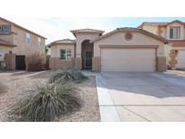 House exterior featuring a two-car garage and well-manicured landscaping at 24201 W Lasso Ln, Buckeye, AZ 85326