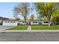 Charming single-story home featuring a lush front lawn, brick walkway, and a two-car garage at 3048 N 45Th St, Phoenix, AZ 85018