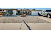 Charming single-story home featuring a two-car garage, rock landscaping, and mature bushes at 5501 E Dallas St, Mesa, AZ 85205
