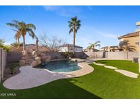 Inviting backyard oasis featuring a sparkling pool, waterfall, and lush landscaping at 2942 S Sierra Hts, Mesa, AZ 85212