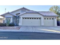 Two-car garage, light-colored stucco exterior, and desert landscaping at 5153 W Pontiac Dr, Glendale, AZ 85308