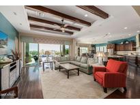 Open concept living room features wood floors, wood beam ceilings, and views of the outdoor pool area at 18111 W Desert Sage Dr, Goodyear, AZ 85338