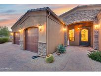 View of the home's entryway, showcasing a three-car garage and a charming front door at 28370 N 113Th Way, Scottsdale, AZ 85262