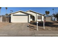 Ranch style home with a two-car garage and a desert landscape at 702 W Grove Cir, Mesa, AZ 85210