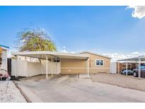 Tan single-wide mobile home with carport and landscaped yard at 10951 N 91St Ave # 56, Peoria, AZ 85345