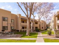 Tan apartment building with mature trees, green grass, and walkways in a well-maintained community at 145 N 74Th St # 207, Mesa, AZ 85207