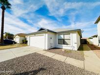 Ranch-style home with a white garage door and gravel driveway at 8728 W Vale Dr, Phoenix, AZ 85037