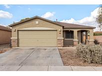 Tan house with a two-car garage and landscaped front yard at 1944 E Saddle Dr, San Tan Valley, AZ 85143