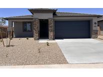 Charming single-story home with a desert landscape, brick accents, a dark garage door, and a covered porch at 20596 N 226Th Dr, Surprise, AZ 85387