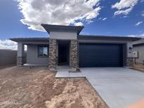 Charming single-story home with a dark blue garage door and complementary stone pillar accents at 20596 N 226Th Dr, Surprise, AZ 85387