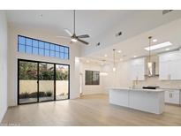 Bright, open-concept living room with large windows and a modern kitchen with white cabinets at 7955 E Chaparral Rd # 116, Scottsdale, AZ 85250