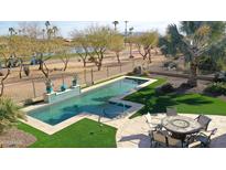 Inviting pool with travertine tile, surrounded by lush landscaping, overlooking a golf course at 2005 N 169Th Ave, Goodyear, AZ 85395