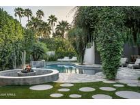 Inviting backyard pool area with a fire pit, lush greenery, lounge chairs, and elegant landscaping at 6529 E Camino De Los Ranchos St, Scottsdale, AZ 85254