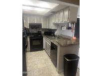 A kitchen featuring stone counters, a tile backsplash, neutral cabinets, and black appliances at 4730 W Northern Ave # 1076, Glendale, AZ 85301