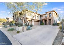 Beautiful home featuring a stone facade and a three-car garage, complemented by desert landscaping at 10260 E White Feather Ln # 1038, Scottsdale, AZ 85262