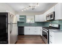 Modern kitchen featuring stainless steel appliances, white cabinets, and green backsplash at 1934 E Brill St, Phoenix, AZ 85006