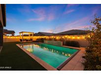 Beautiful backyard featuring a swimming pool with a waterfall feature, turf, landscaping, and a pergola with lights at 4752 S Orbit Ave, Mesa, AZ 85212