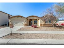 Front view of a tan house with a two-car garage and desert landscaping at 14400 N 136Th Ln, Surprise, AZ 85379